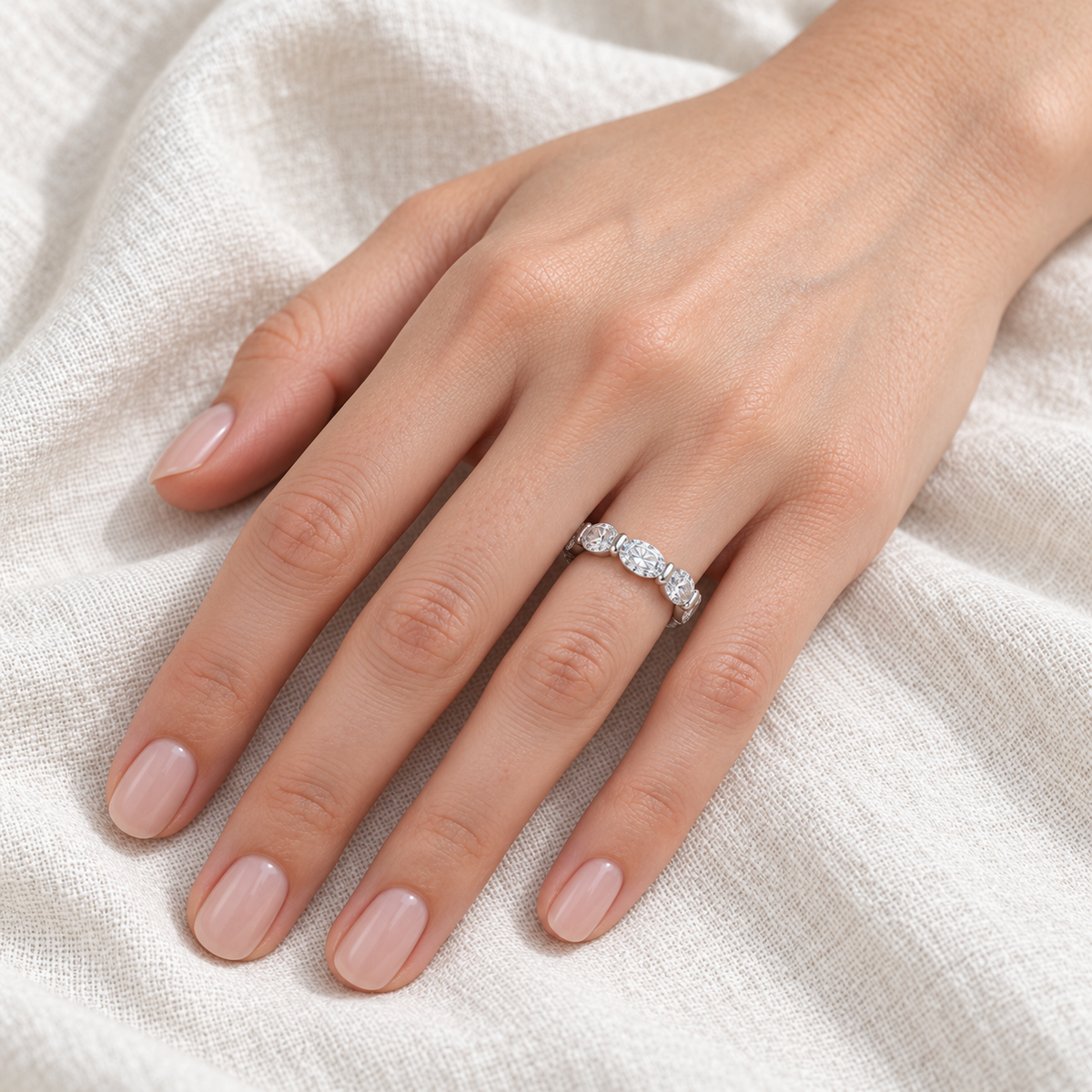 East-west oval shared-prong lab-grown diamond eternity band, 5 x 3 mm diamonds, 14K white gold, on-hand view