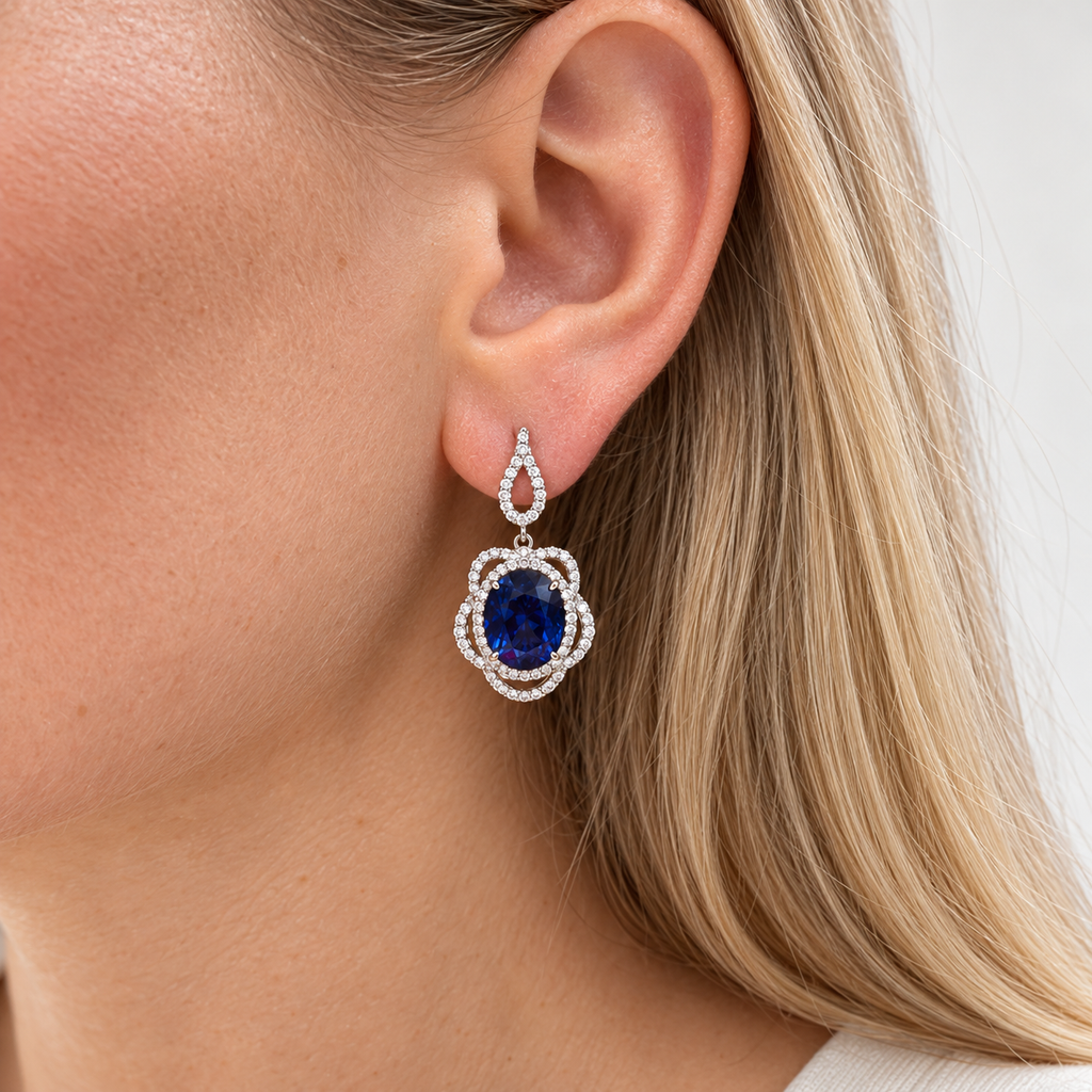Oval blue sapphire and diamond drop earrings worn on ear
