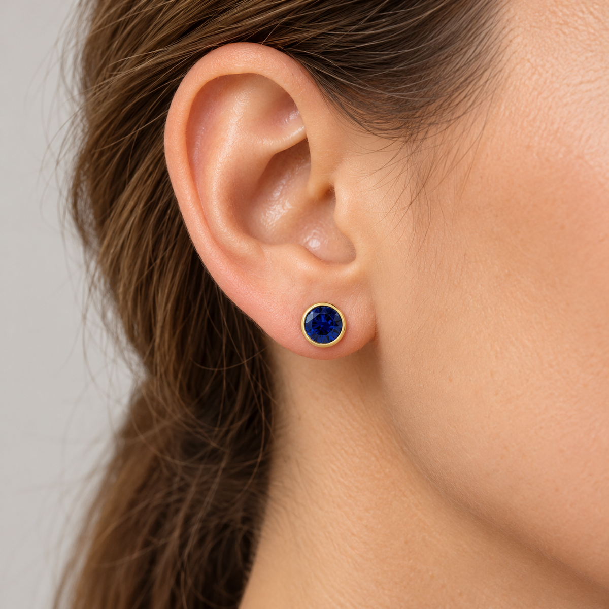 14K Gold Lab-Grown Gemstone Bezel Stud Earrings — Lab-Grown Blue Sapphire / 14K Yellow Gold / 6 mm — illustrative on-ear view
