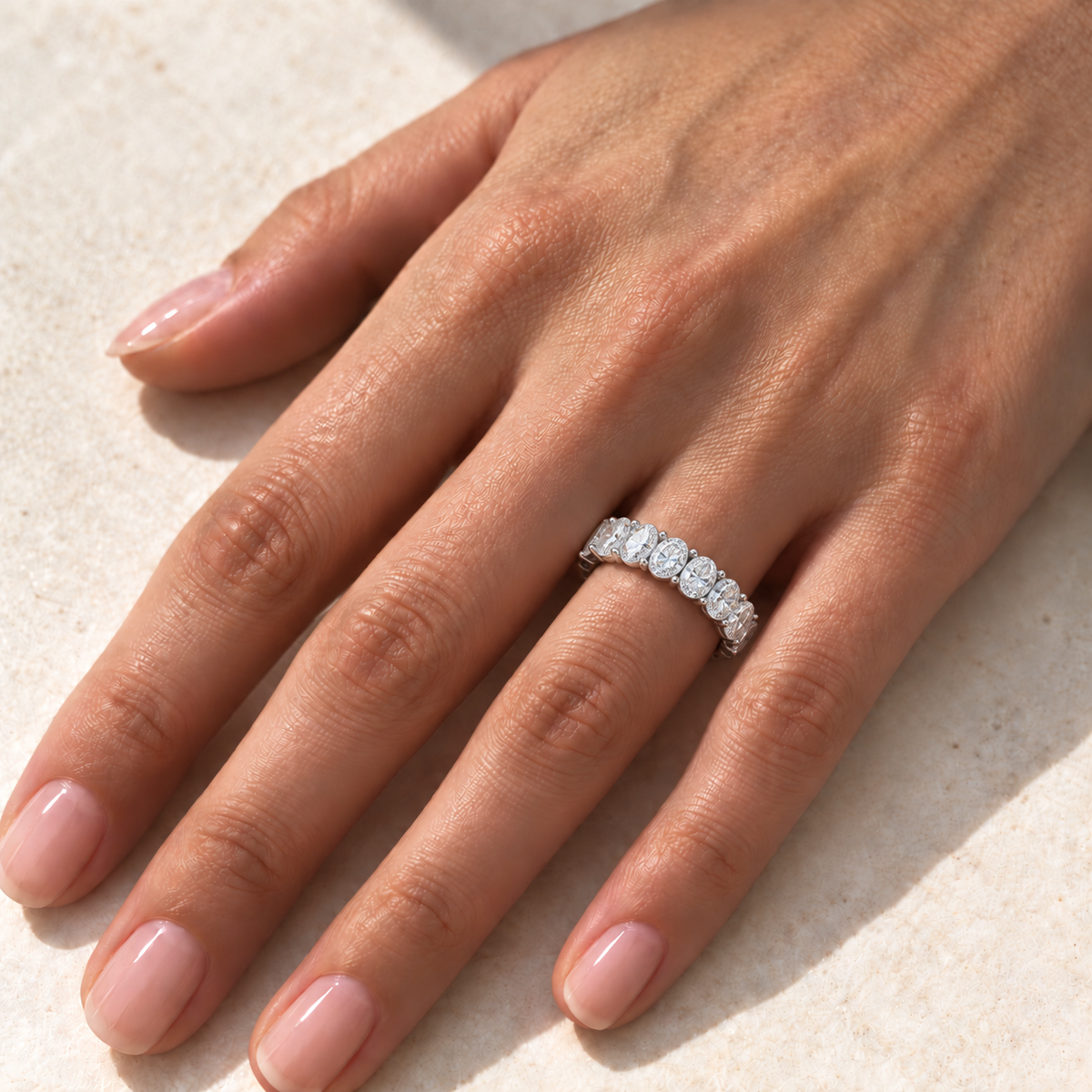 Oval lab-grown eternity band 3.00 x 4.00 mm, white metal, hand view