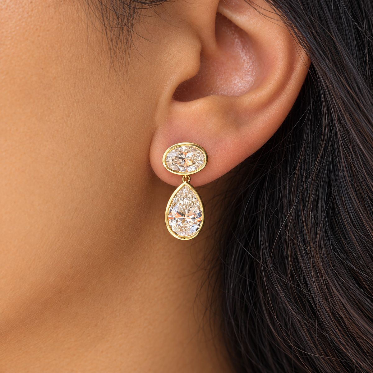 Oval and pear yellow gold diamond drop earring worn on ear